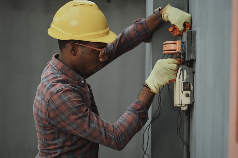 Electricien avec gants rouges de protection devant un tableau &eacute;lectrique